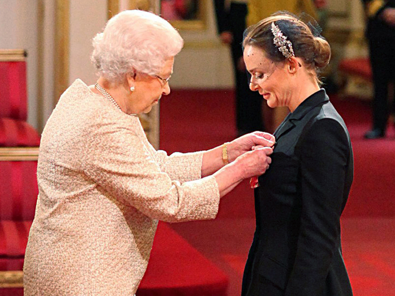A rainha Elizabeth II condecorando Stella McCartney, em 2013