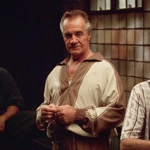 Paulie Walnuts (Tony Sirico) de The Sopranos usando um conjunto de tracksuit nude e marrom com o seu clássico penteado com mechas platinadas. 