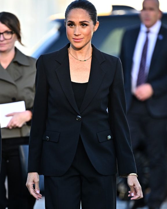 Meghan Markle reinventa o all black em viagem a Genebra com toque de veludo